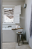 Freestanding bathtub under a window with shutters in the bathroom