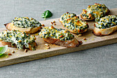 Gratinated crostini with spinach, cheese and pine nuts