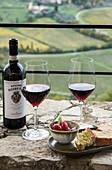 Zwei Gläser Rotwein vor italienischer Landschaft