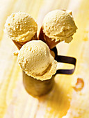 Three ice cream cones with mango ice cream in a metal cup