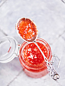 Blood orange jam in a mason jar with a spoon