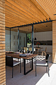 Dining table on roofed terrace of modern, architect-designed house