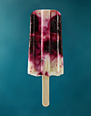 A blueberry yogurt popsicle against a blue background
