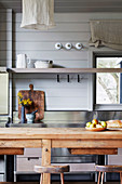 View over wooden dining table onto kitchen shelf