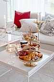 Pastries on golden cake stand on coffee table in living room