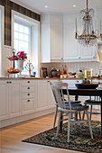 Spoke-back chairs at round table in classic, white kitchen