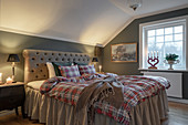 Tartan bed linen on bed with valance in cosy bedroom