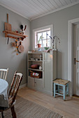 Alter Schrank vor grauer Wand in schlichter Wohnküche