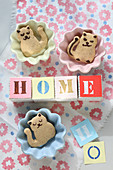 The word 'Home' on paper cubes and cat-shaped biscuits in dishes