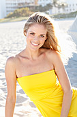 Blonde Frau in gelbem Bandeau-Kleid am Strand