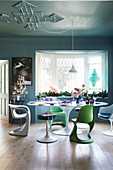 Bunt gedeckter Tisch mit Designerstühlen vorm Erkerfenster