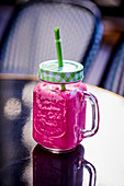 Pink smoothie in a glass with a straw
