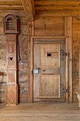 Antique longcase clock next to panelled door in rustic farmhouse parlour