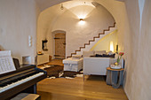 Klavier im rustikalen Wohnzimmer mit Gewölbe und Treppe