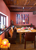Gedeckter Tisch im urigen Esszimmer mit Eckbank und roten Wänden