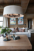 Round lampshade above coffee table in living room of log cabin