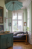 Parasol above sofa in window bay with mint-green walls in period building