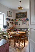 Round wooden table and wainscoting with picture ledge in cosy dining room