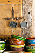 Colourful, rustic ceramic bowls stacked in front of wooden door