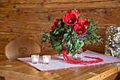 Strauß mit roten Amaryllis, Efeu und Efeubeeren auf einem Holztisch