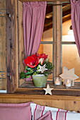 Arrangement with amaryllis and wooden stars on windowsill of farmhouse parlour