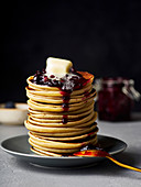 A stack of pancakes with jam and butter