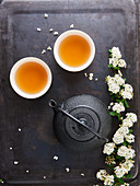 Teeschalen, Teekanne und weiße Blüten