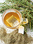 Thyme tea in a glass cup with a tea bag