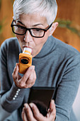 Senior woman using spirometer at home