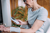 Senior woman doing wrist physical therapy with TENS