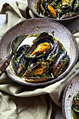 Mediterranean style dinner. Close up of table with Mussels in green sauce and white wine.