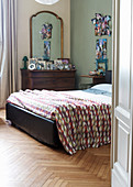 Double bed and antique chest of drawers with mirror in bedroom