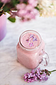 Strawberry smoothie with lilac flowers