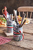 Tins of cutlery on a rustic wooden table