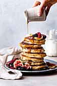 Maple syrup poured over a stack of pancakes.