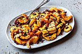 Roasted delicata squash with pomegranate and pistachios on a plate.