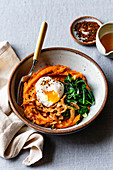 Closeup view of a sweet potato breakfast bowl with coconut bacon, spinach and poached egg.