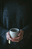 A woman holding a cup of fresh tea