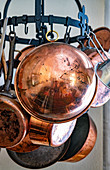 Old copper pans on a metal hanging rack
