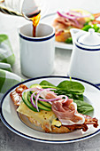 Breakfast sandwich with prosciutto, avocado, eggs and bacon