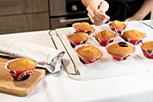 Frisch gebackene Cupcakes mit Schokoladenglasur beträufeln