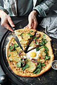 Potato and spinach pizza with anchovies and a fried egg
