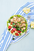 Light summer gluten free lunch bowl with buckweat, cucumber, tomatoes and prawns on lettuce leaves