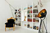 Gilt carved Louis XV armchair in white room with built-in shelving and theatrical light