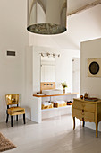 Glamouröser goldener Stuhl im weißen offenen Badezimmer mit französische Kommode