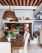 Large metal pendant lamps above wooden dining table with steps in background