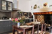 Old fireplace and 19th century table in modern kitchen