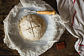 Ungebackener Brotlaib mit eingeritztem Kreuz
