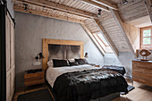 Luxurious double bed in bedroom with wooden ceiling and skylight