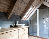 Waschtisch aus Holz und Duschbereich im Badezimmer im Dachgeschoss